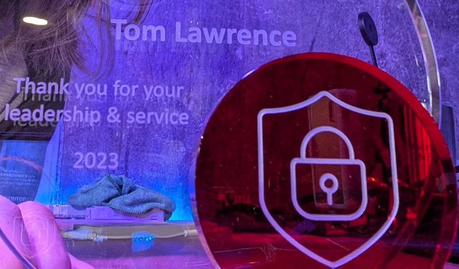 Glass award engraved: Tom Lawrence, Thank you for your leadership and service, 2023, with a red shield and lock emblem
